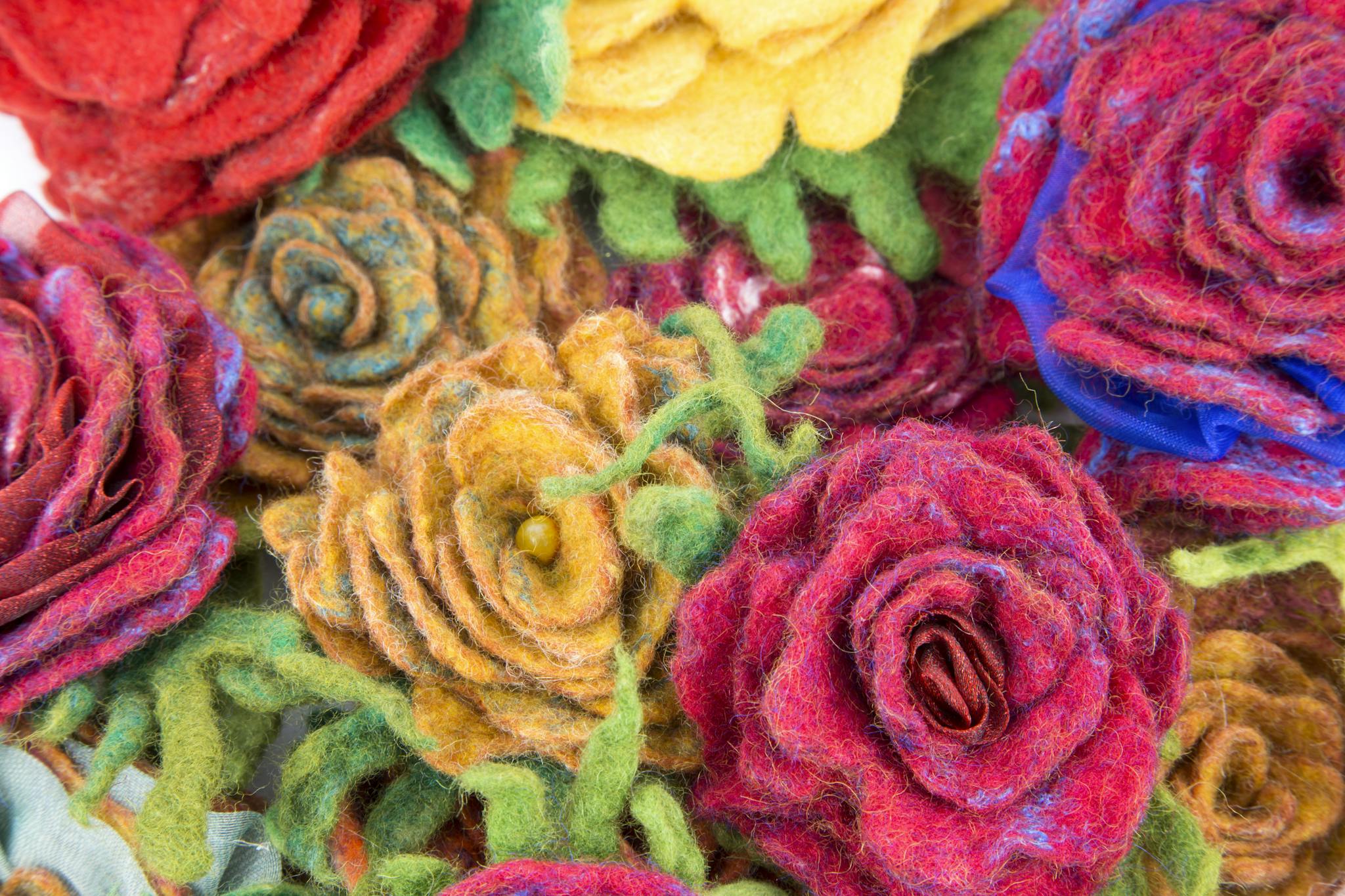 A close-up of vibrant handmade felt roses with rich textures and colors.